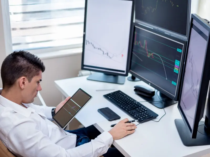 Trader analysing charts on multiple monitors